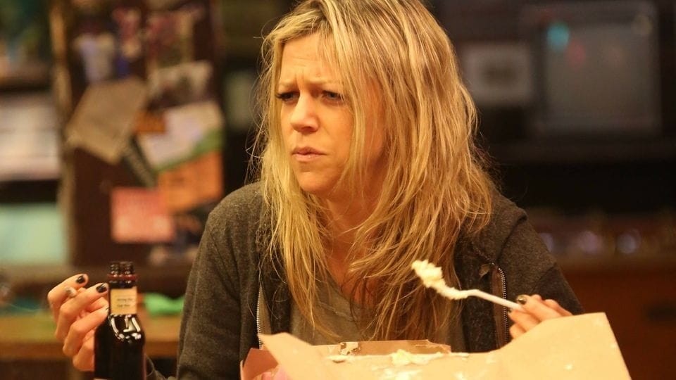 Dee from It's Always Sunny, looking like she hasn't slept in days. She's eating cake found in the garbage.