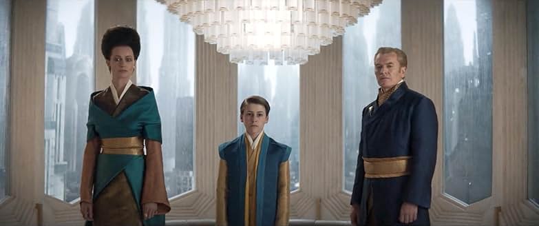 Two parents and a young child stand awkwardly looking at the other family. They are dressed in blue. The windows look out on Coruscant behind them.