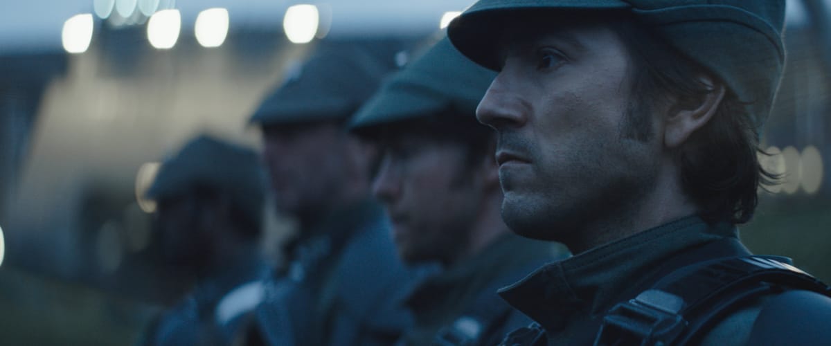 Four men are lined up dressed up as Imperial soldiers. They angle from right to left, front to back, and become blurry the farther back.