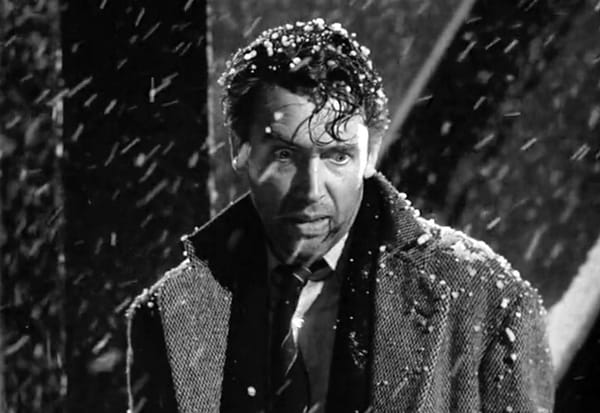 George Bailey (Jimmy Stewart) stands on a bridge as it snows in It's a Wonderful Life